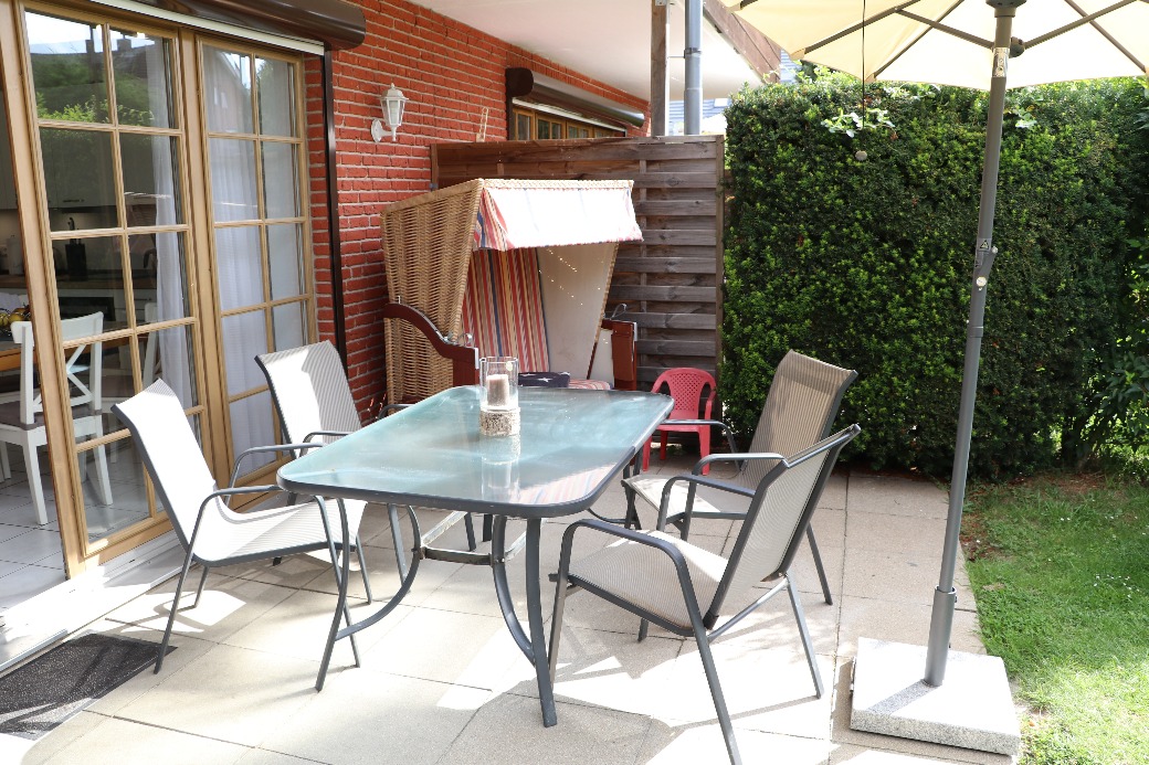 Tischgruppe auf der Terrasse von Haus Henning, mit Strandkorb im Hintergrund.